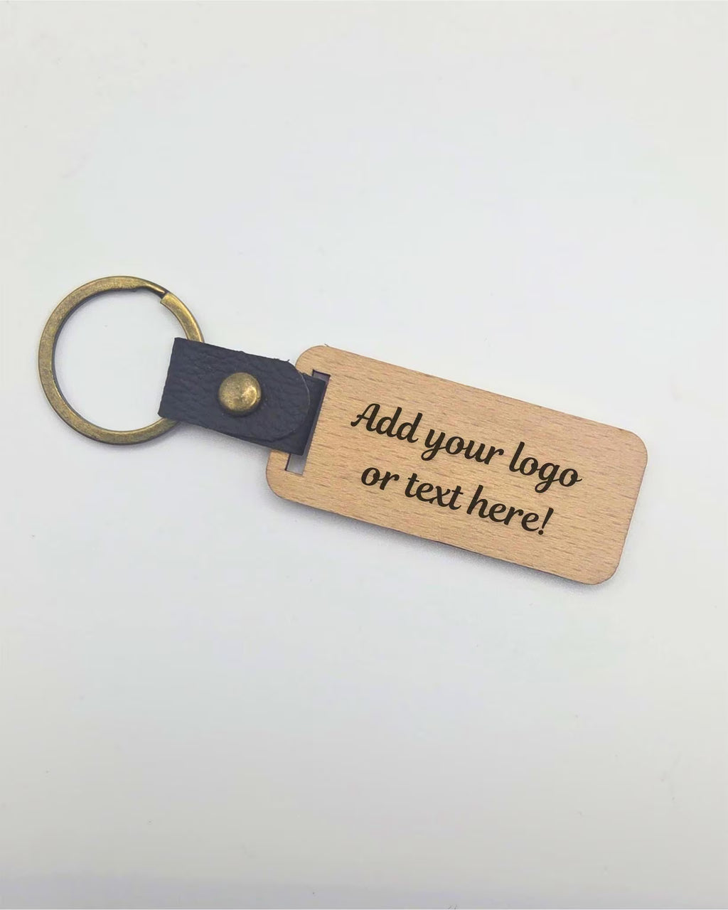 A customizable wooden keychain tag with a dark gray leather strap and brass key ring, featuring placeholder text that reads 'Add your logo or text here!'.