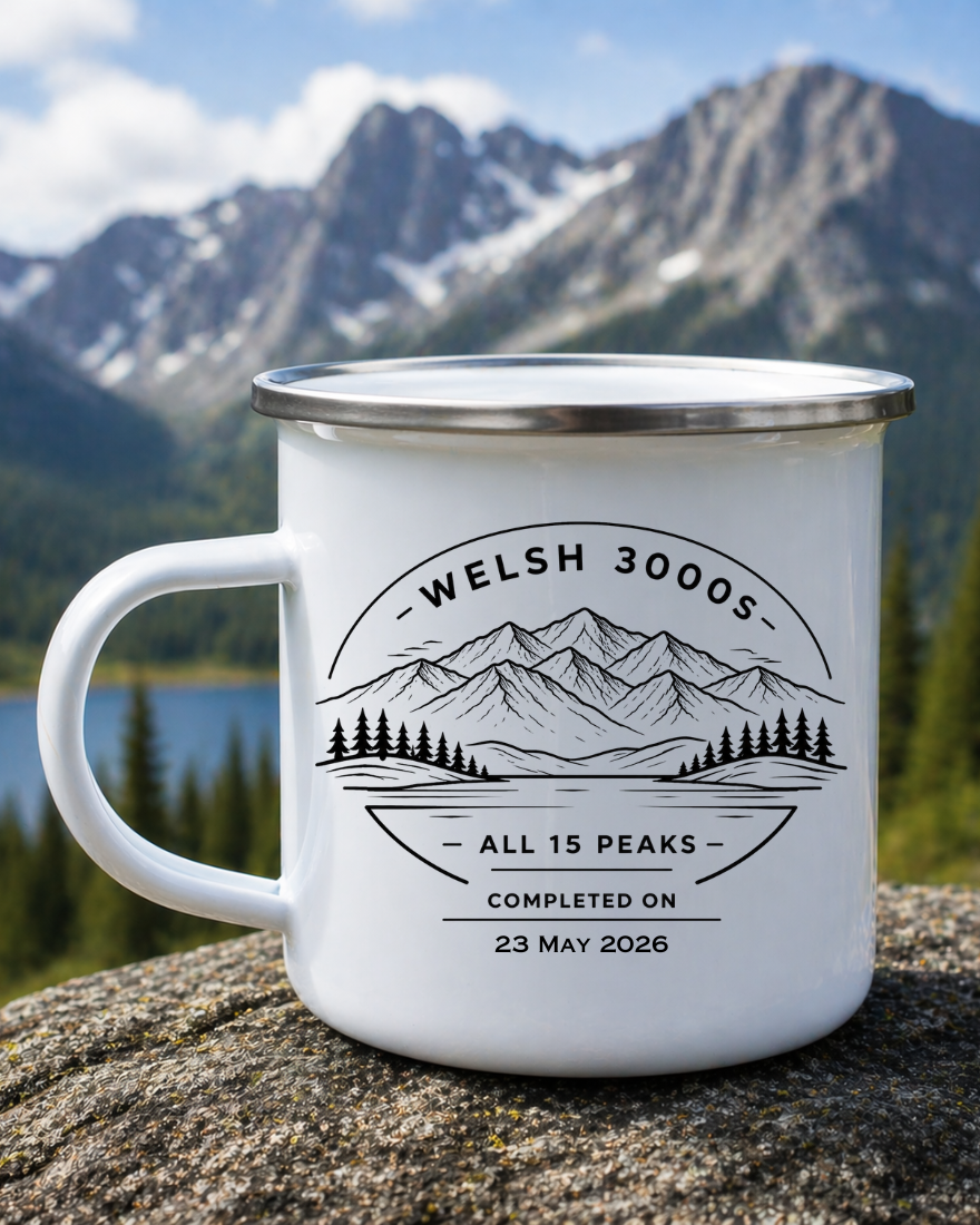 White enamel mug with mountain design and text on a rock with a scenic background