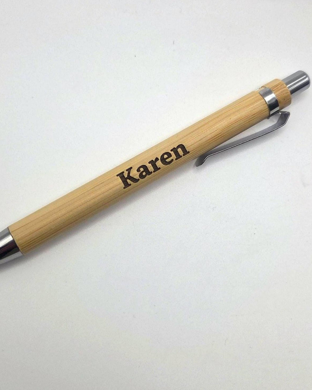 A personalized bamboo ballpoint pen with a silver metal clip, silver tip, and silver end cap, featuring the name 'Karen' engraved on the wooden barrel, shown on a plain white background.