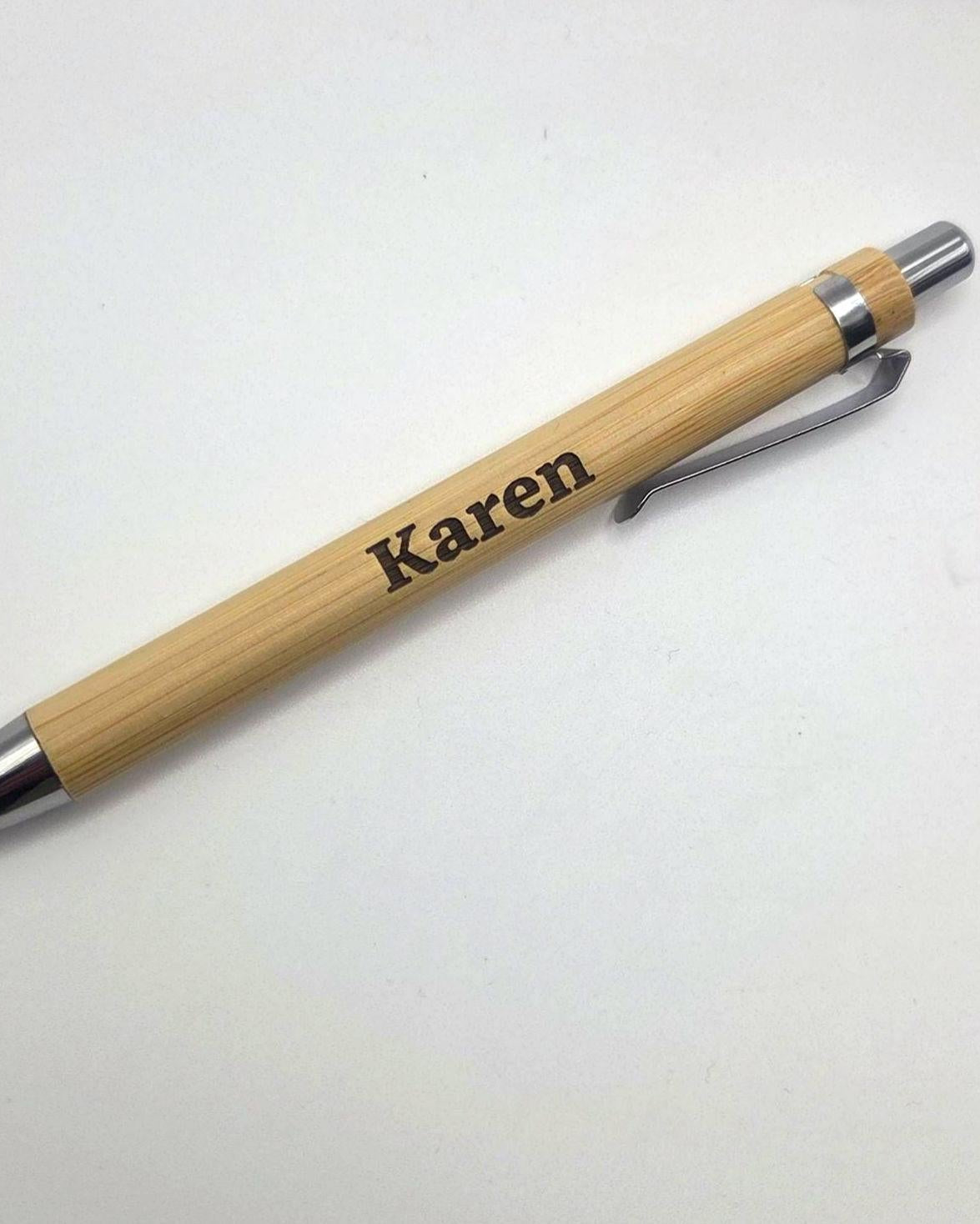 A personalized bamboo ballpoint pen with a silver metal clip, silver tip, and silver end cap, featuring the name 'Karen' engraved on the wooden barrel, shown on a plain white background.