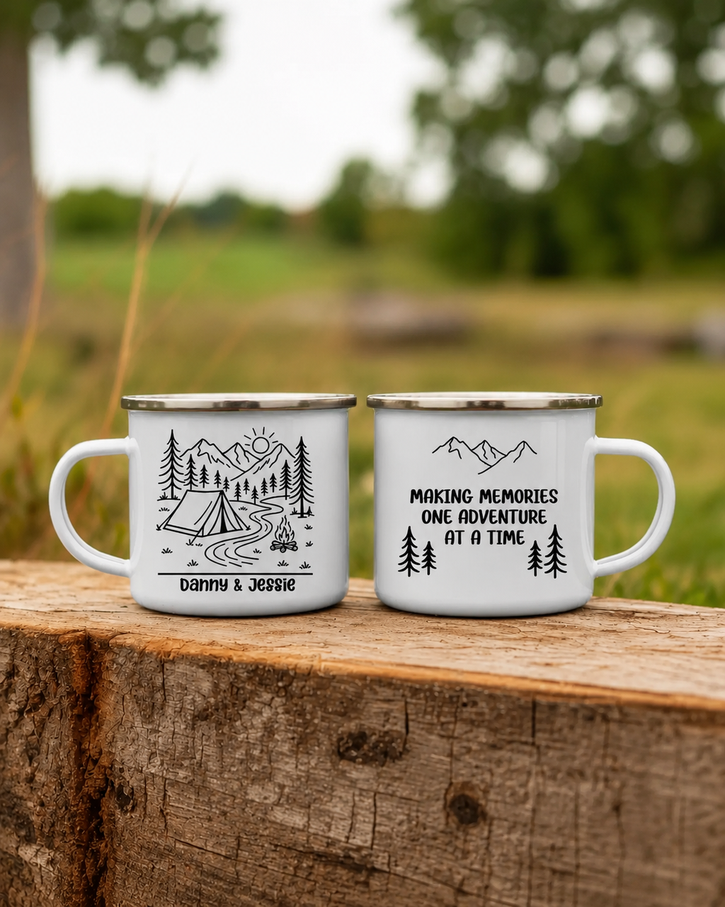 Two white enamel camping mugs with black printed graphics and text, displayed side-by-side on a rustic wooden log with a blurred outdoor background.